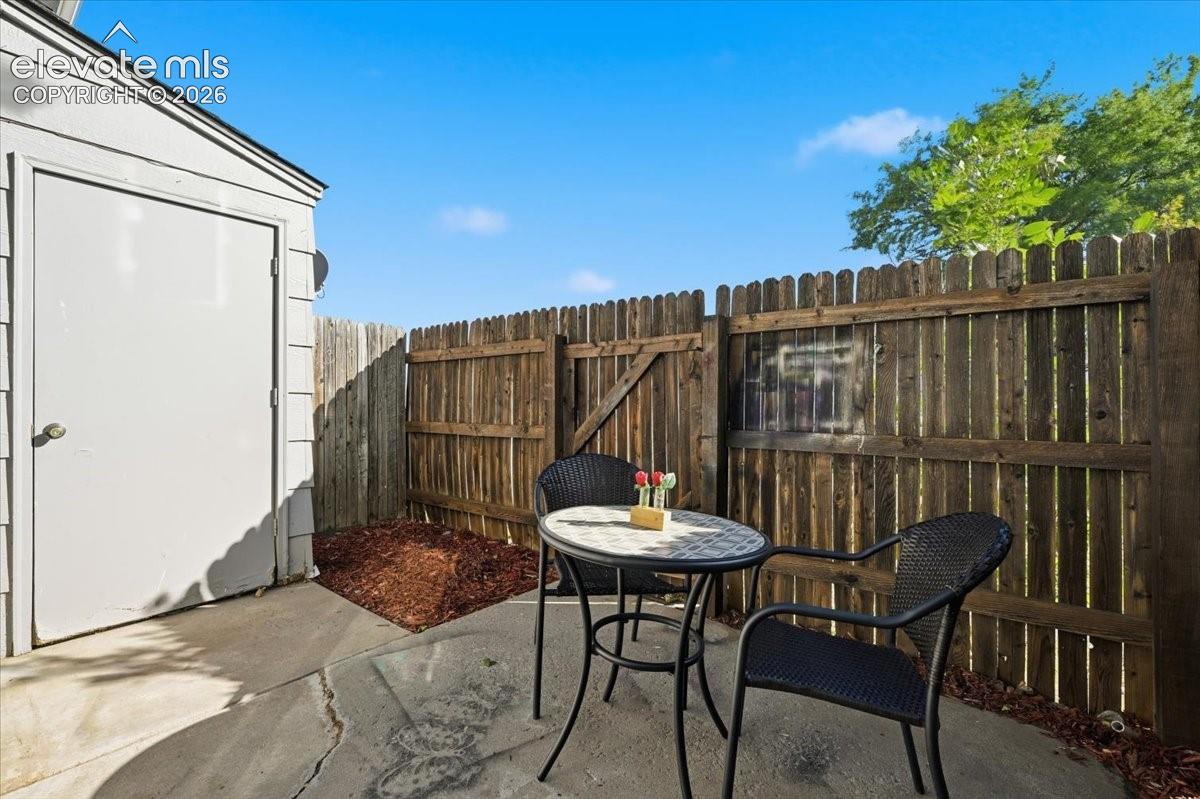Private patio area with concrete surfacing, enclosed by a wood privacy fence