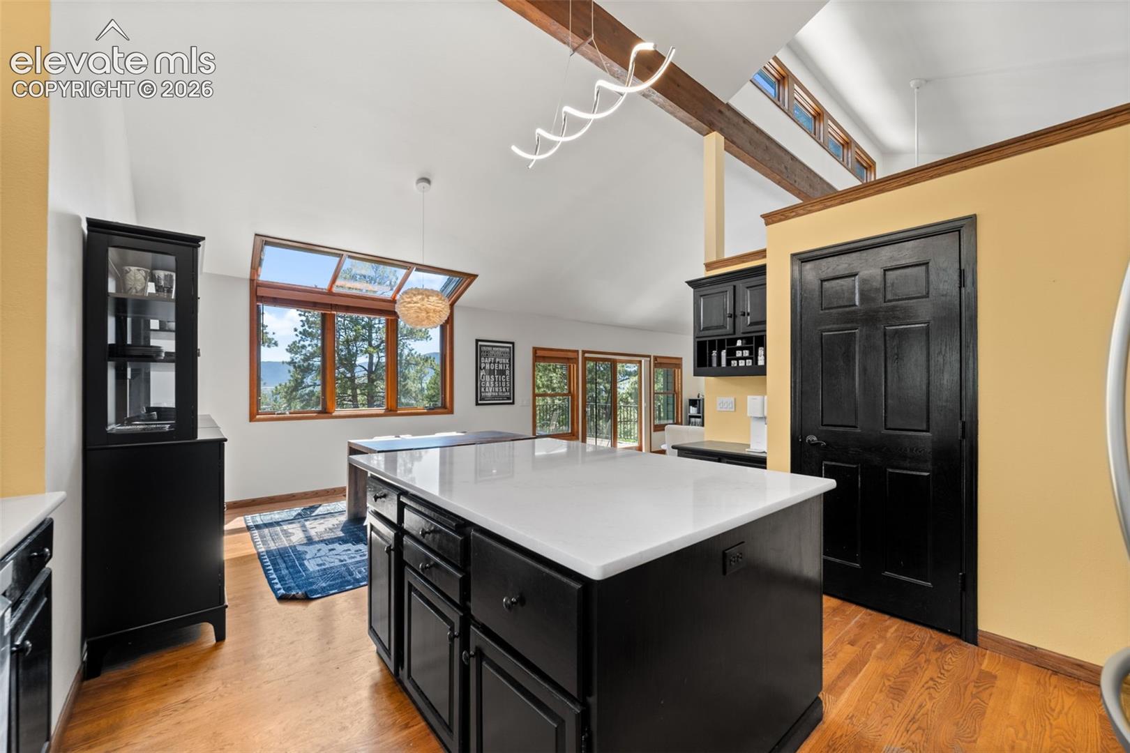 Kitchen featuring a large central island with a white countertop and dark cabinetry