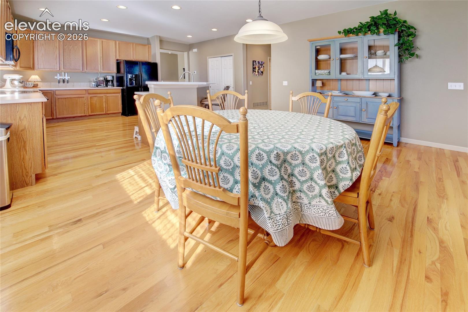 Kitchen featuring light-finish wood cabinetry, solid-surface countertops, and wood-finish flooring