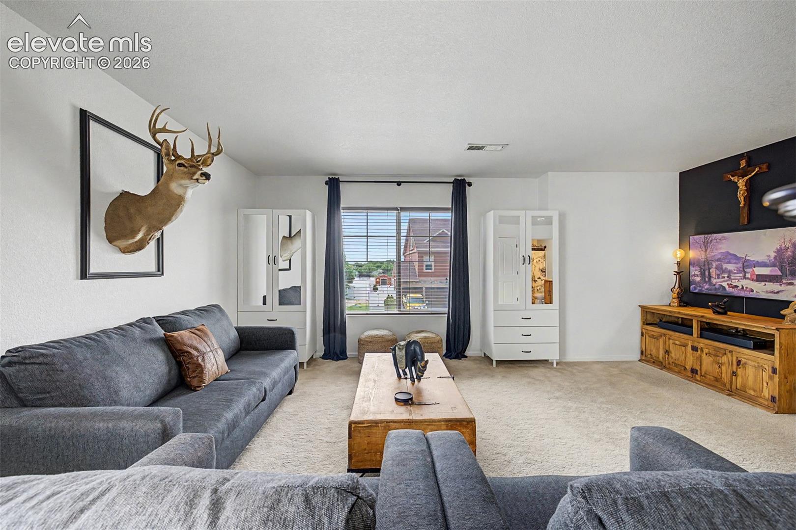The upstairs bonus room offers a relaxed retreat with plush sofas, a media console, and plenty of natural light, the ideal hangout space for family or guests.
