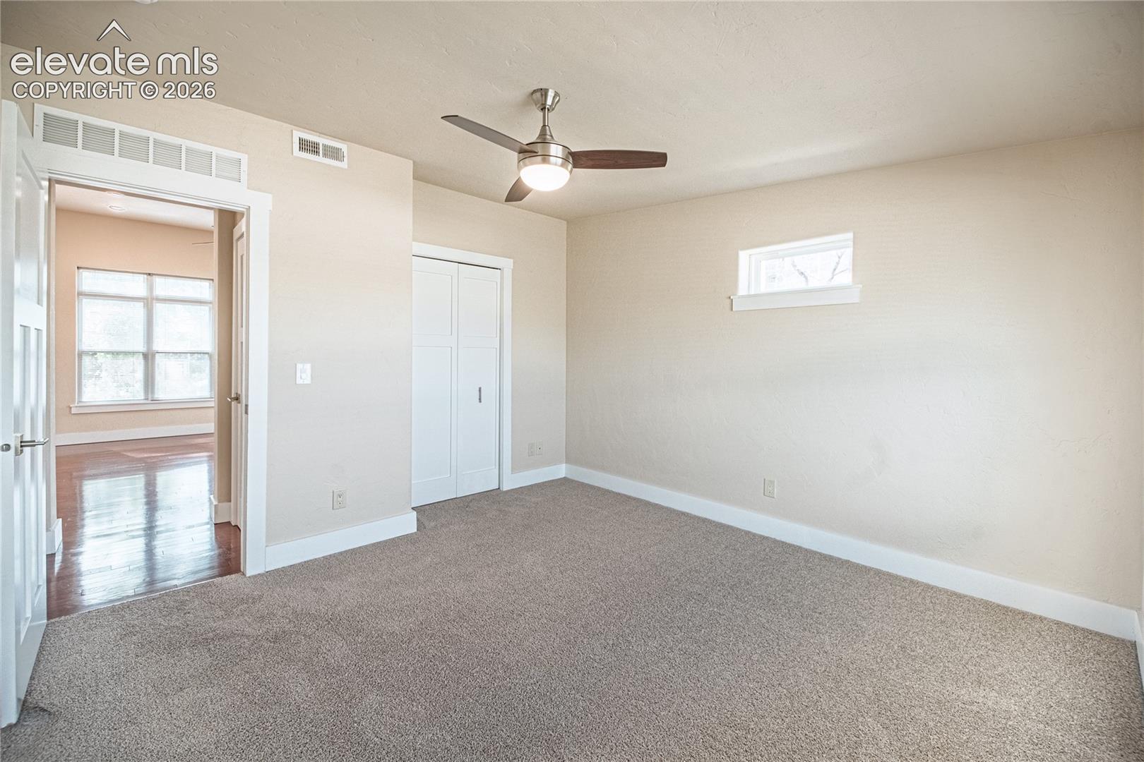 Carpeted room featuring a ceiling fan with integrated lighting, a horizontal window, and a bi-fold closet door