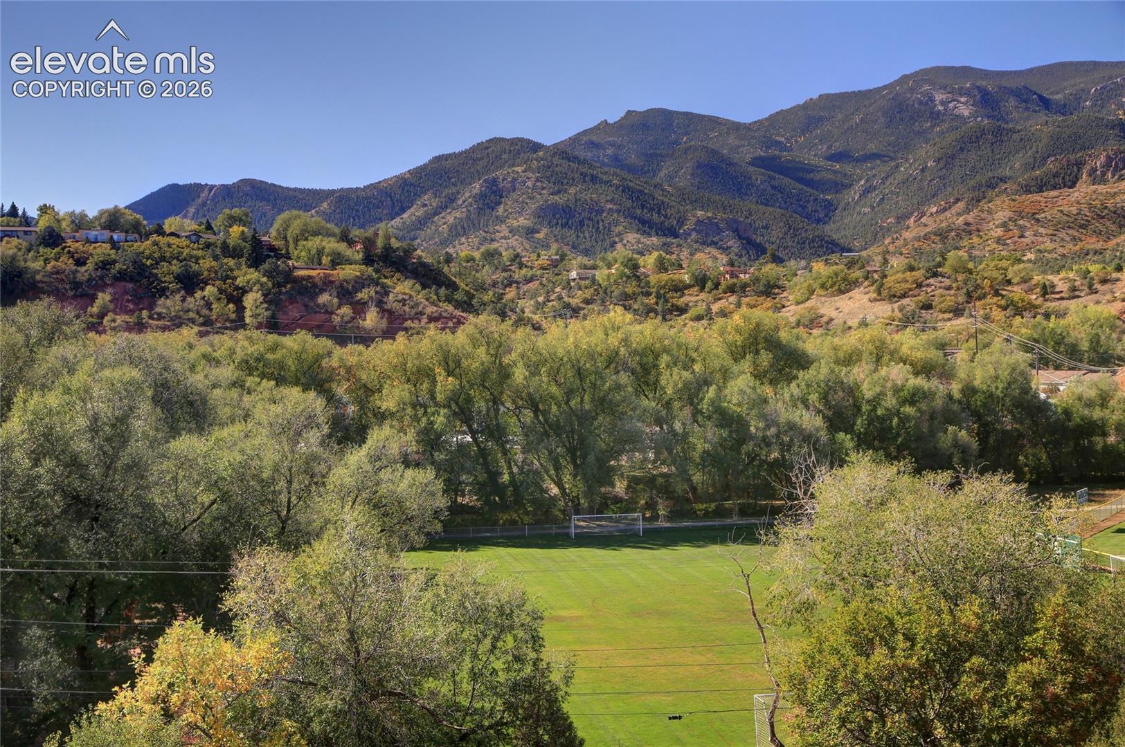Expansive green space featuring a soccer goal, mature trees, and a mountain backdrop