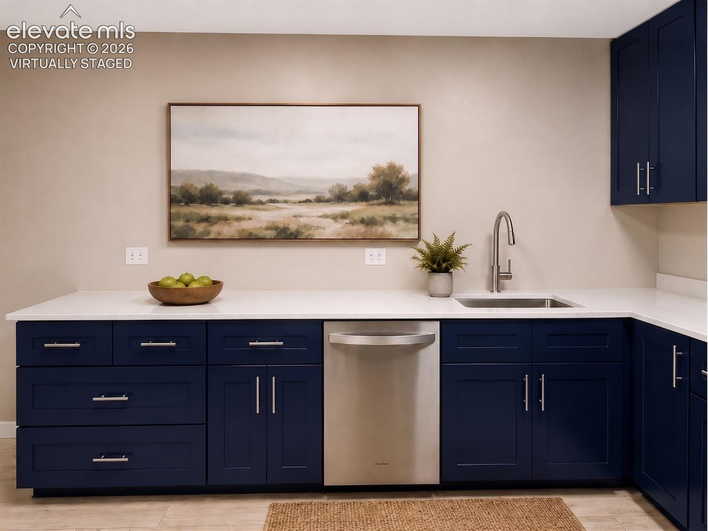 virtually staged L-shaped countertop featuring an undermount stainless steel sink with a gooseneck faucet, white solid surface countertop, and navy blue cabinetry with brushed nickel hardware