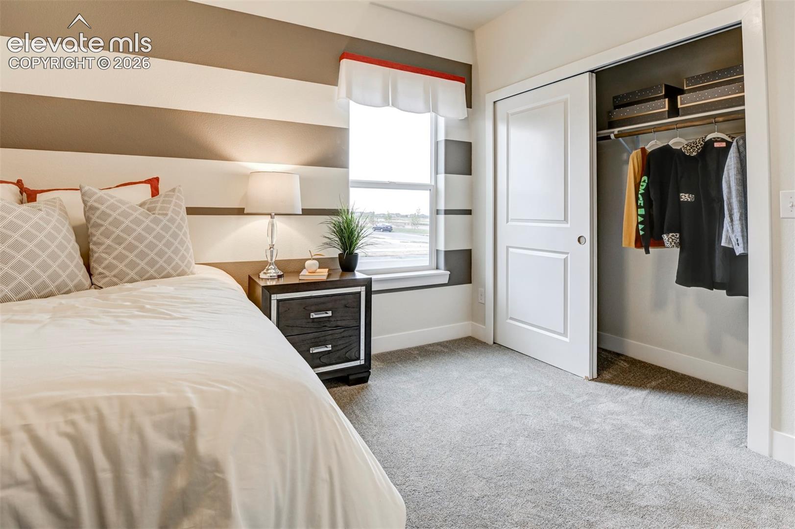 Wall-to-wall carpeting, window with a window ledge, sliding closet doors, and horizontal striped wall treatment