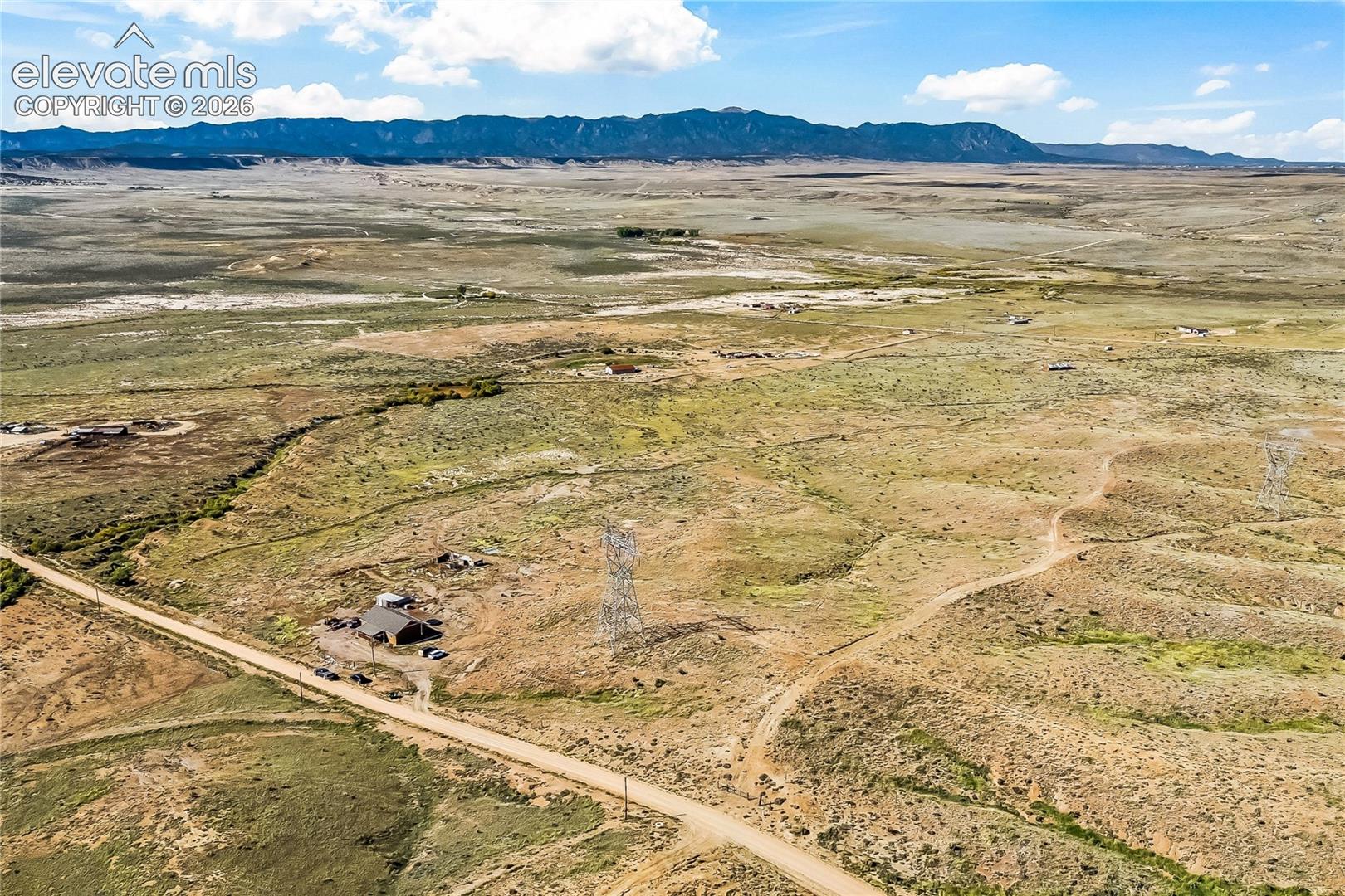Expansive desert acreage featuring native vegetation, unpaved road access, and mountain range backdrop