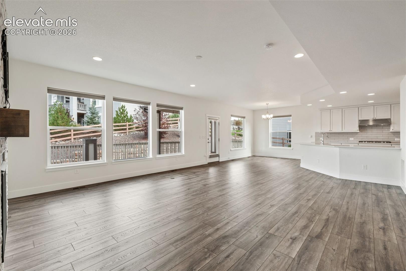 Spacious open-concept living area featuring wood-finish LVP flooring, recessed lighting, and an integrated kitchen/breakfast nook