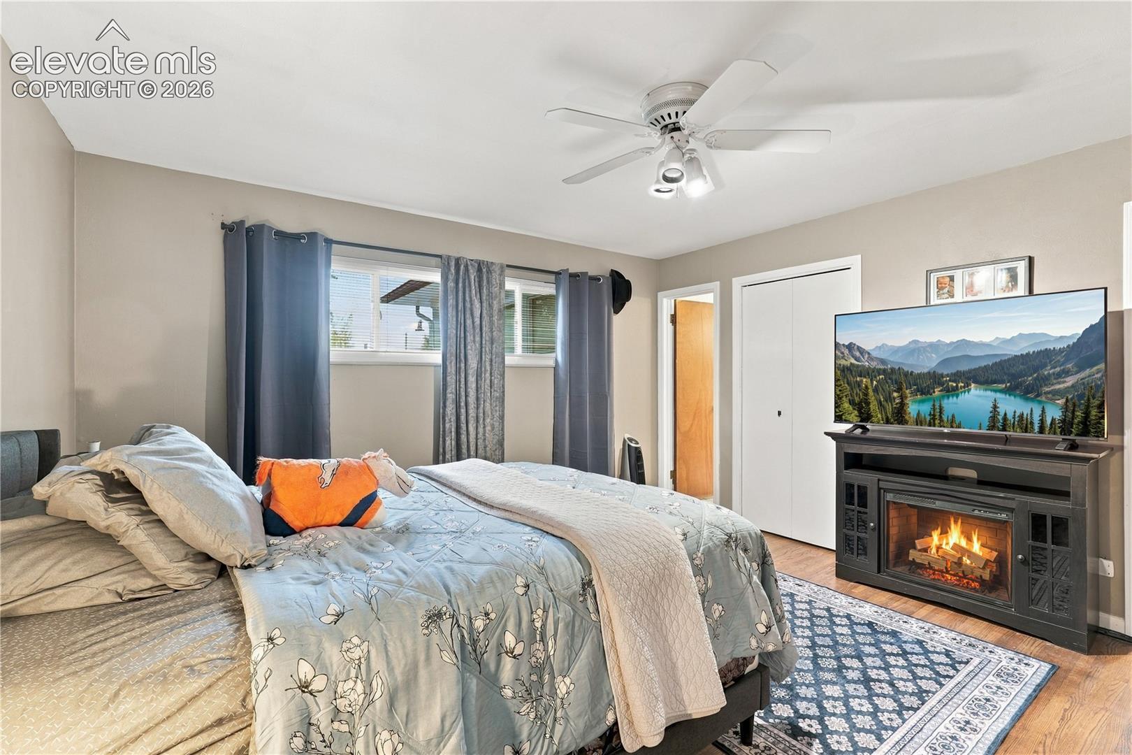 Neutral-toned interior featuring ceiling fan with integrated lighting, sliding closet doors, and wood-finish flooring