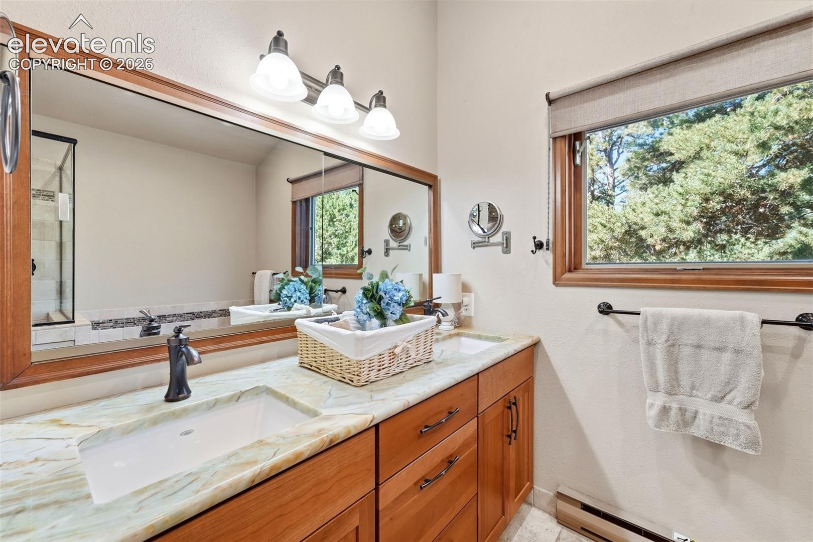 Dual vanity with integrated rectangular sinks, wood-finish cabinetry, and a large wall-mounted mirror