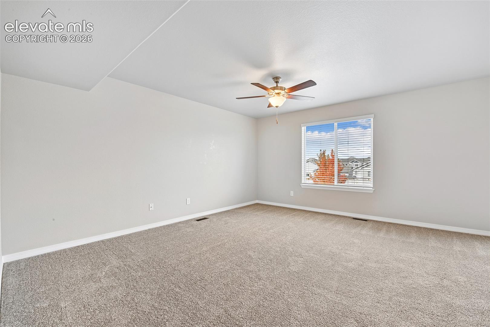 Neutral-toned carpeting, high-gloss ceiling fan with integrated lighting, and a window with horizontal blinds