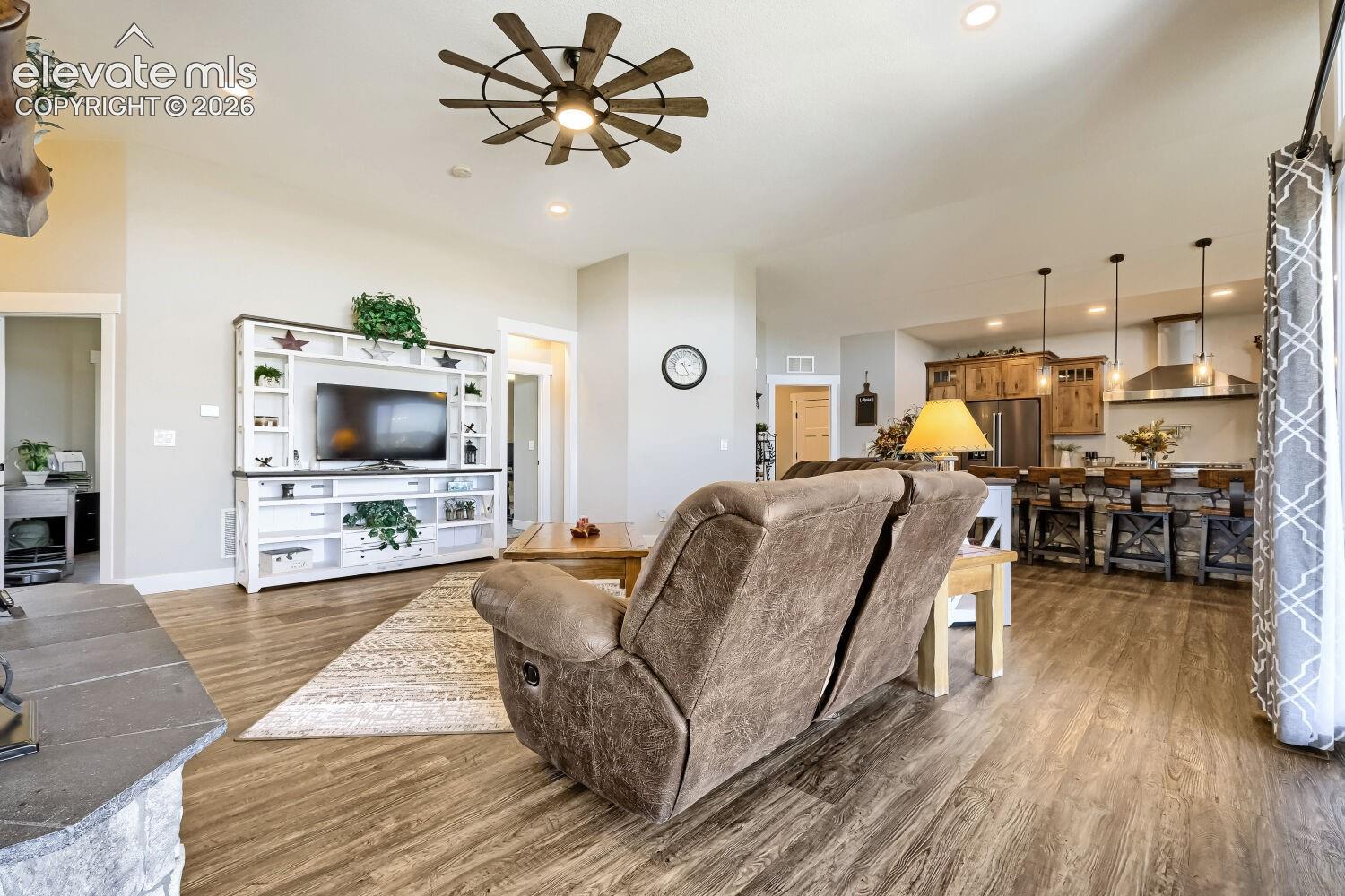 Expansive open-concept living area featuring wood-finish flooring, a decorative ceiling fan, and recessed lighting