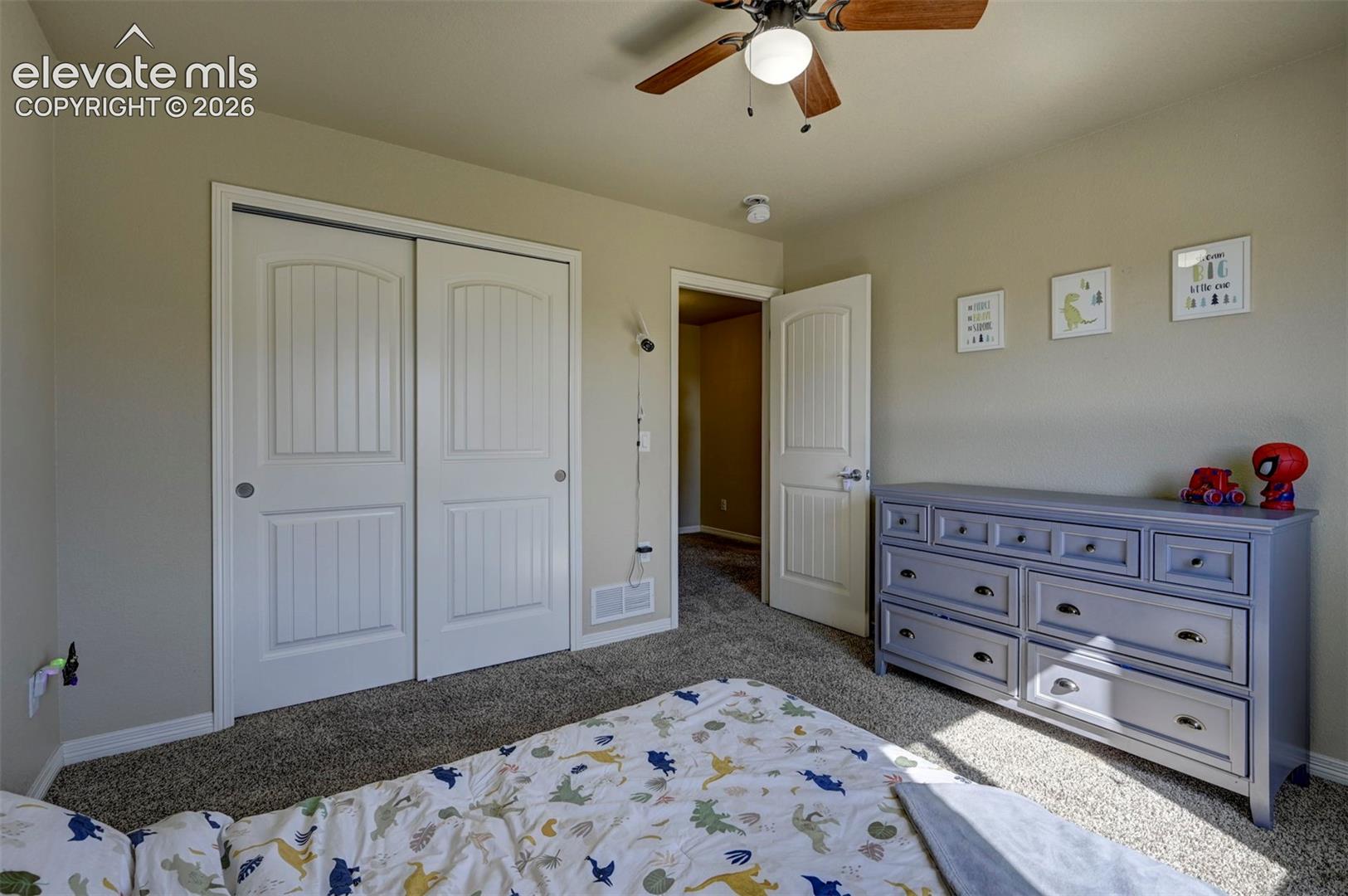 Neutral-toned walls, textured carpeting, white paneled doors, and a ceiling fan with integrated lighting