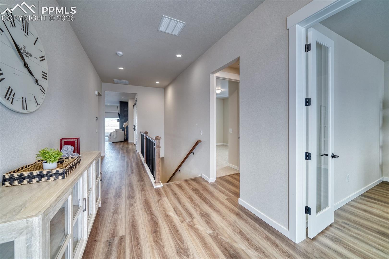 Corridor featuring an upstairs landing, light wood finished floors, and recessed lighting