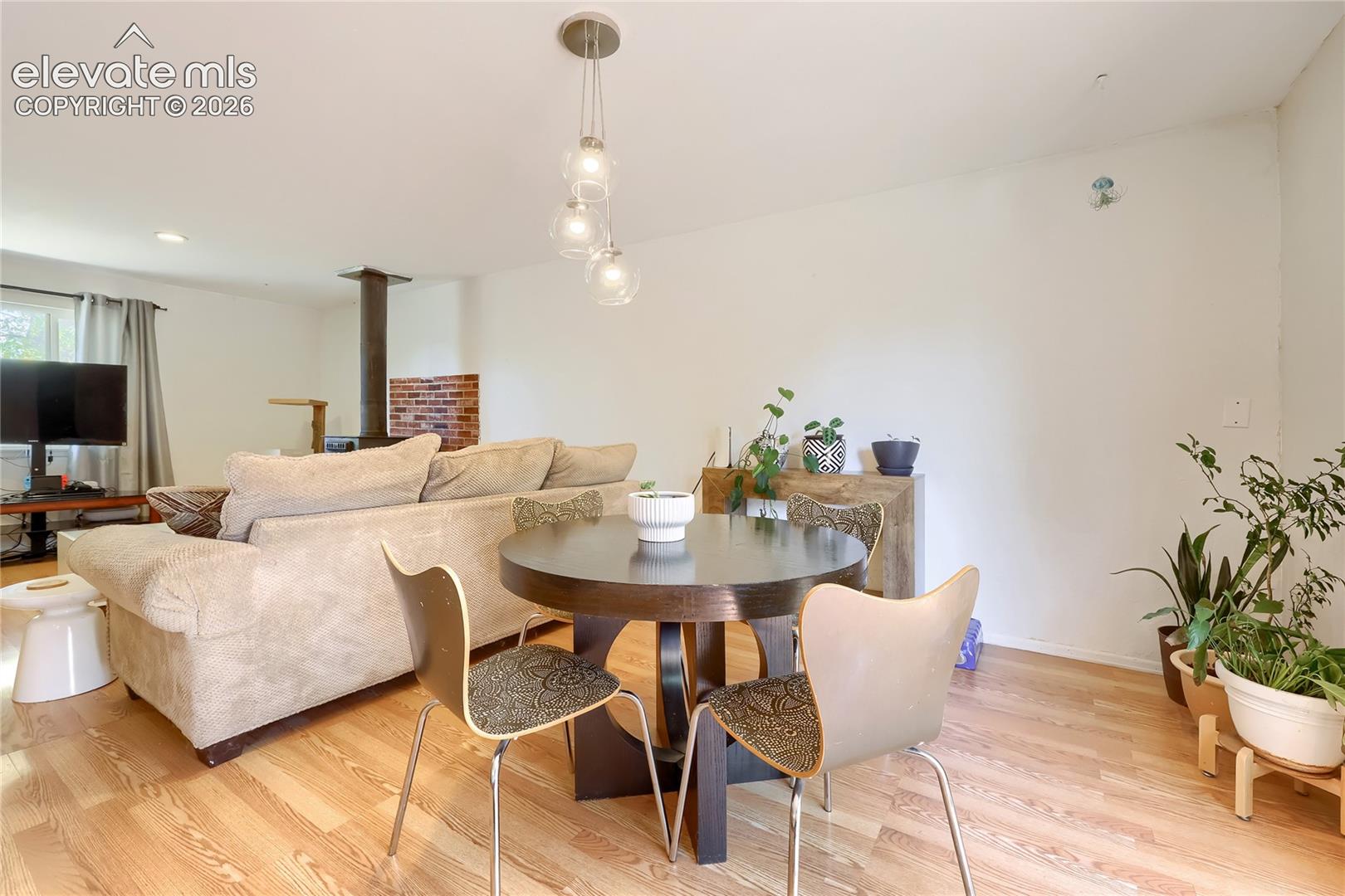 Wood-finish flooring, three-globe pendant lighting, and a brick-accented wood-burning stove