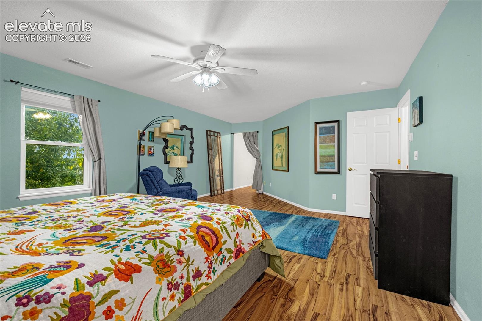 Wood-finish flooring throughout, white trim, and a ceiling fan with integrated lighting