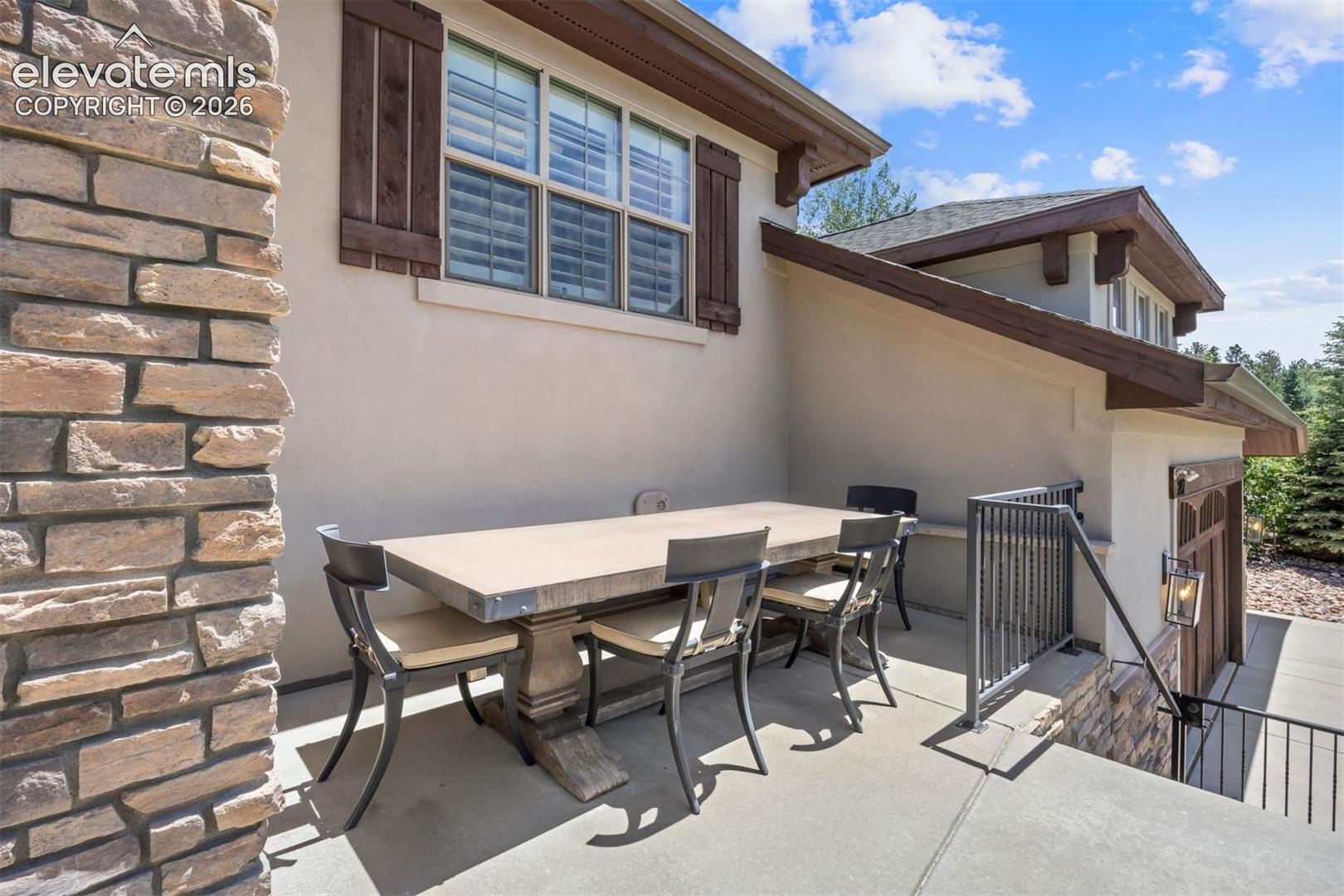 Spacious outdoor patio with a concrete surface, stone veneer accent wall, and stucco exterior