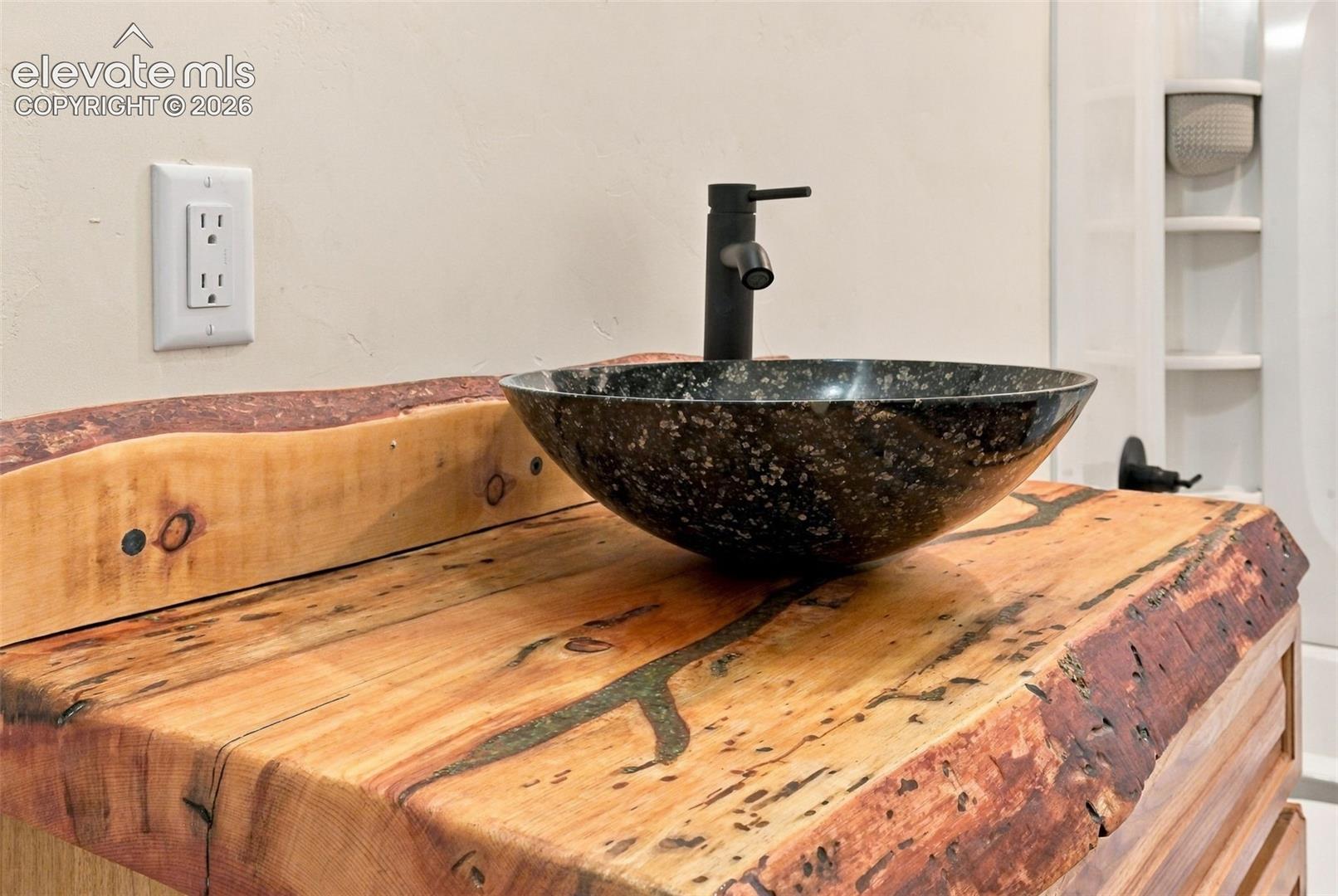 Live-edge wood vanity countertop, circular stone-finish vessel sink, and matte black single-handle faucet