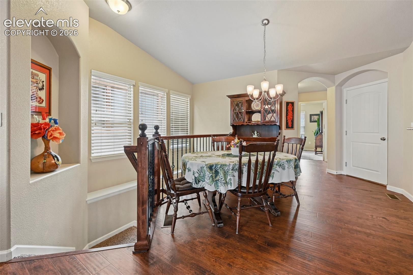 Dining area featuring vinyl flooring, an arched doorway, and a chandelier