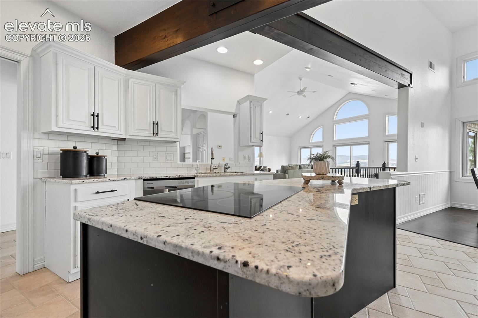 Kitchen island with integrated cooktop, granite countertop, and dark cabinetry