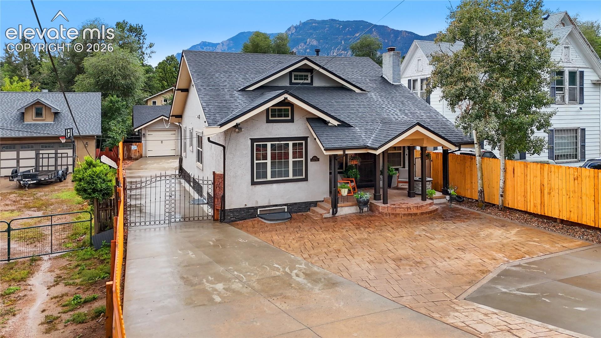 Charming bungalow-style residence featuring a covered front porch with brick columns, a prominent gable roofline, and a stamped concrete driveway