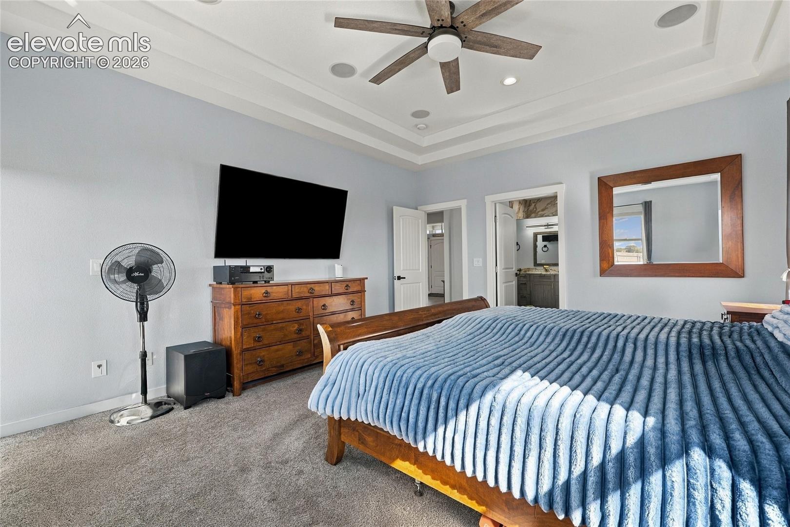 Tray ceiling featuring a central wooden-blade ceiling fan and integrated recessed lighting