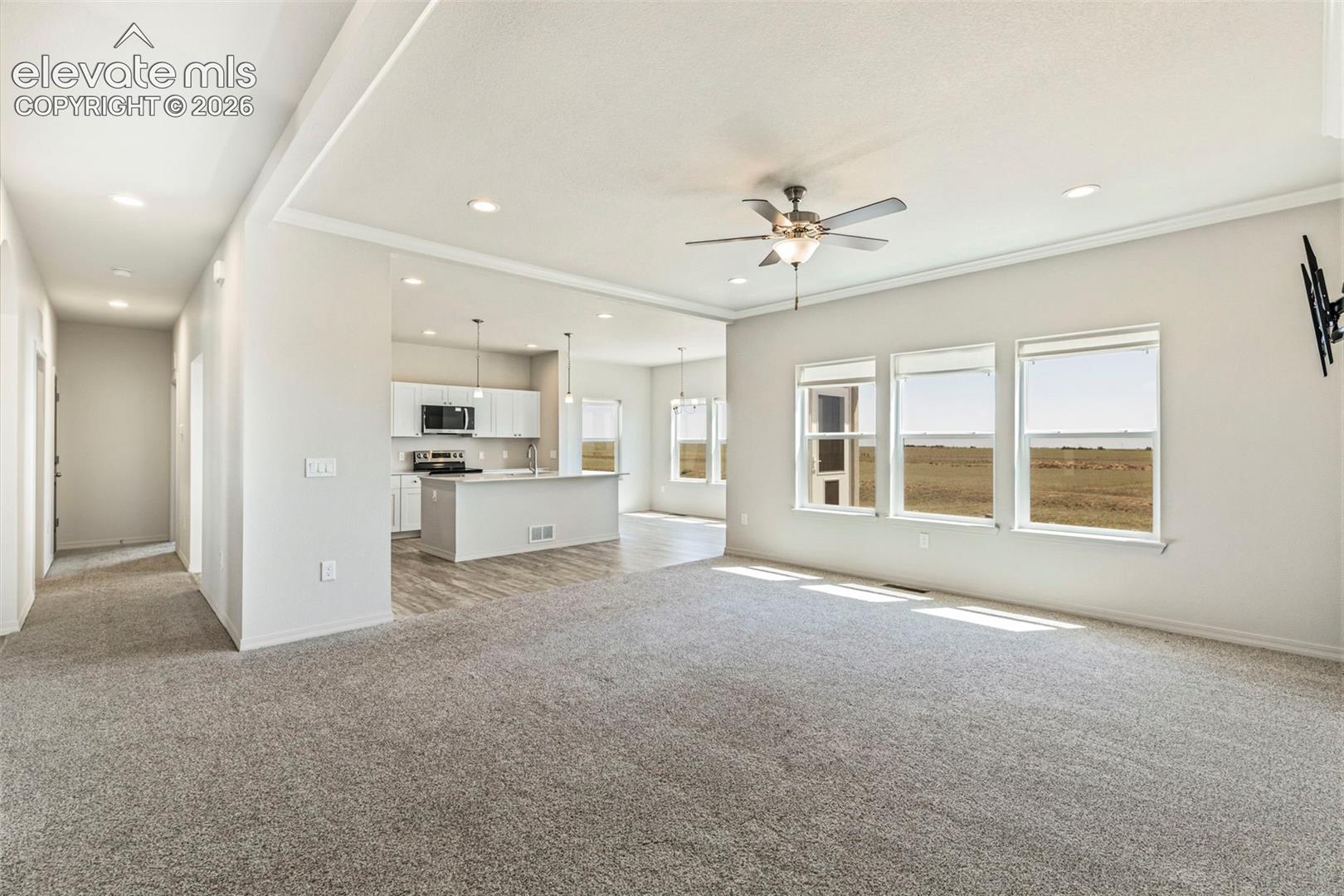 Spacious living area featuring light gray carpeting, recessed lighting, and a ceiling fan