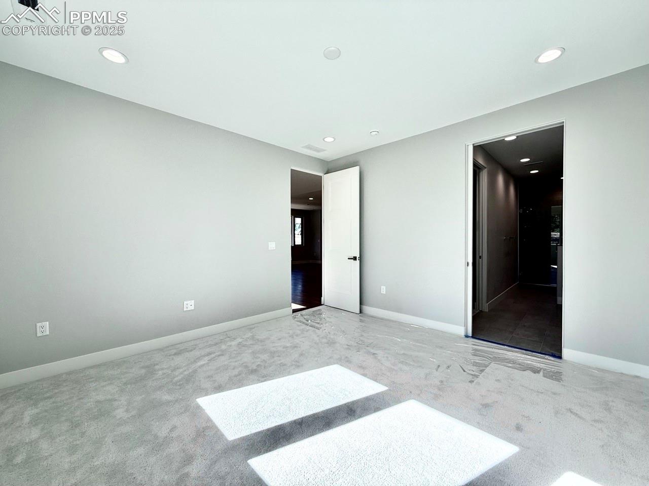 Main Level Primary Suite with Large Windows looking into the Forest and Carpeting.
