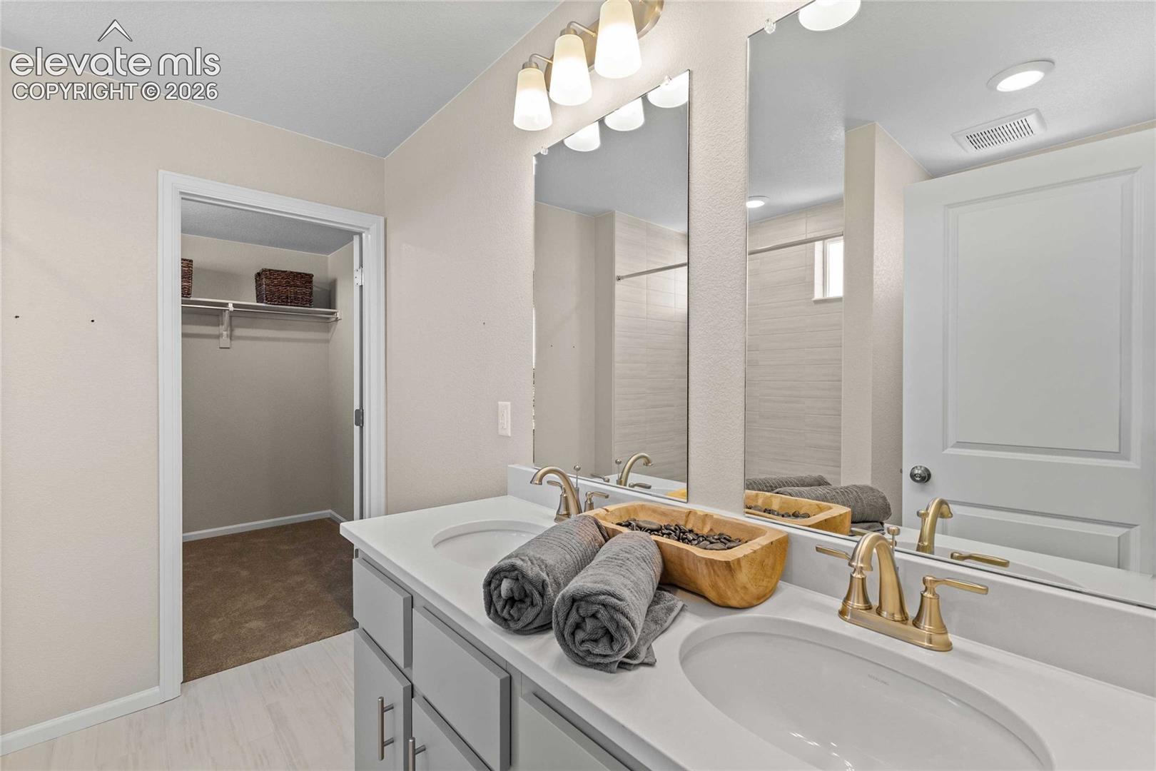 Dual vanity with gold-finish faucets and undermount sinks, illuminated by an overhead light fixture
*photos of a model home*