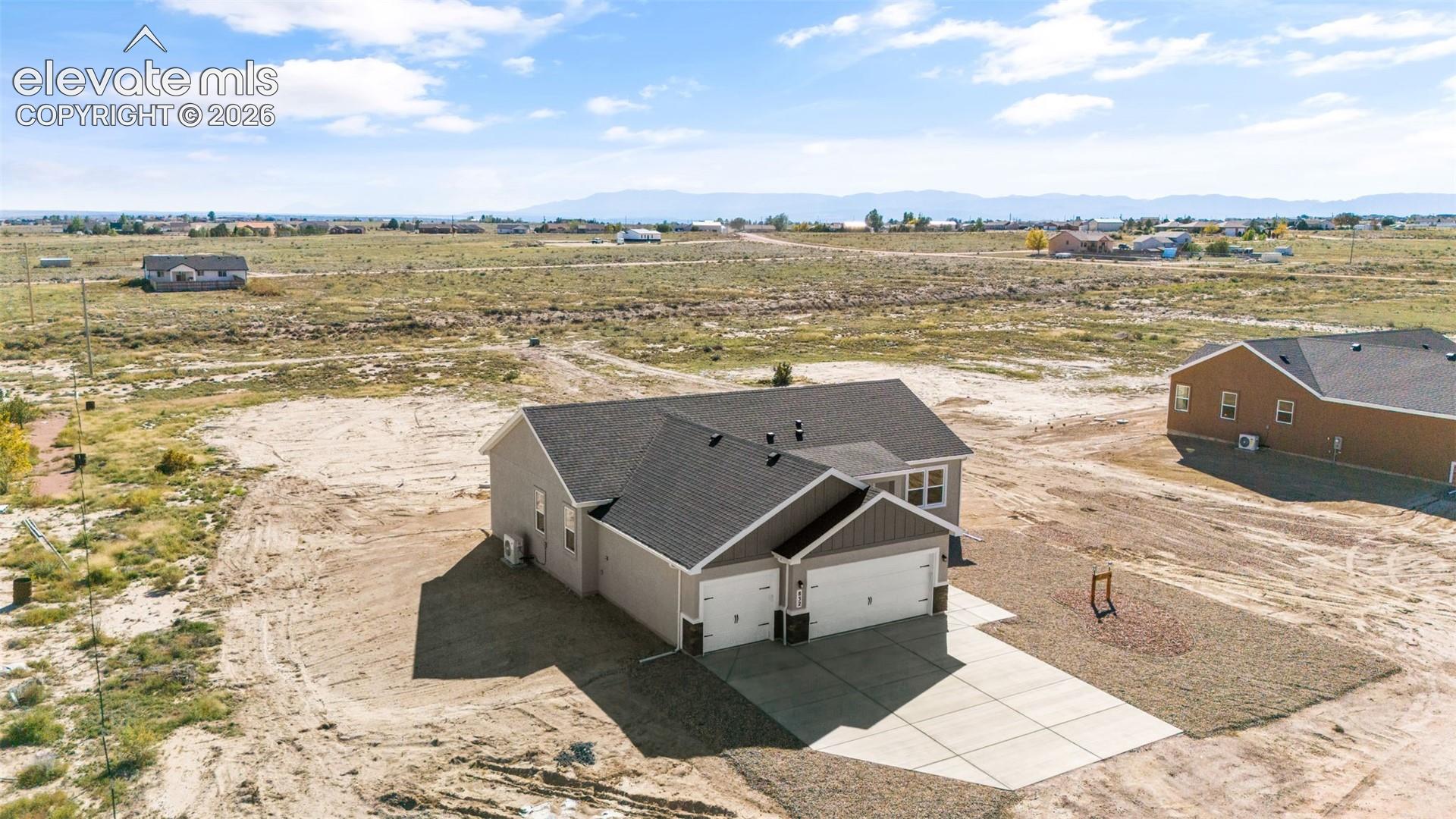 Single-story residence featuring a multi-gabled roofline, two-car garage, concrete driveway, and mountain backdrop