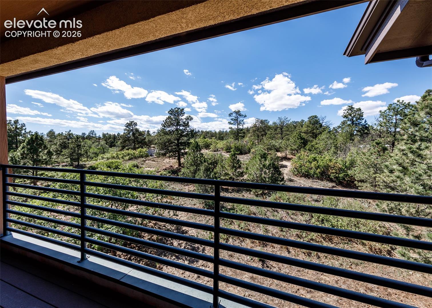Covered balcony featuring horizontal metal railing and natural woodland scenery
