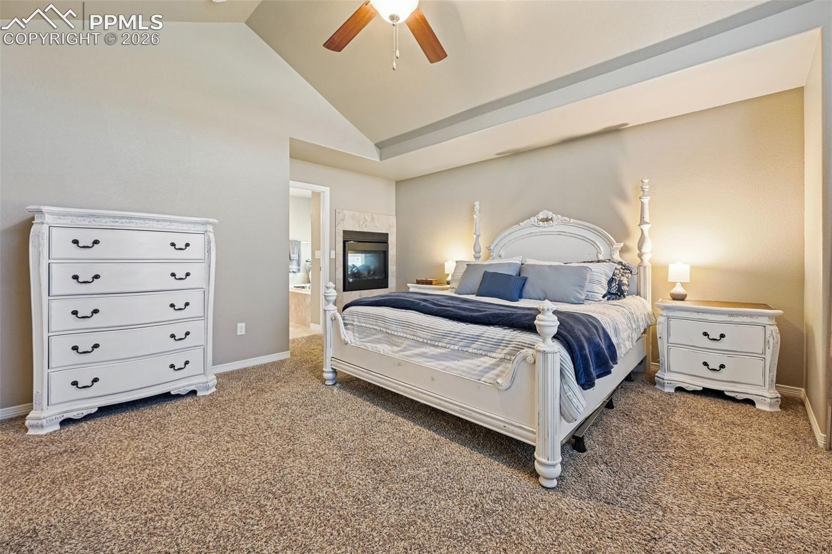 Bedroom featuring vaulted ceiling, carpet flooring, ceiling fan, and ensuite bathroom