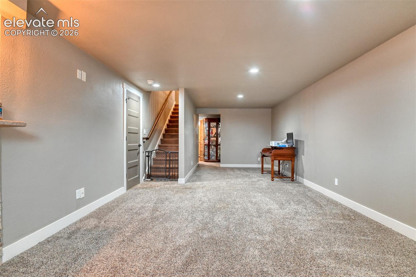Finished below grade area with light colored carpet and recessed lighting