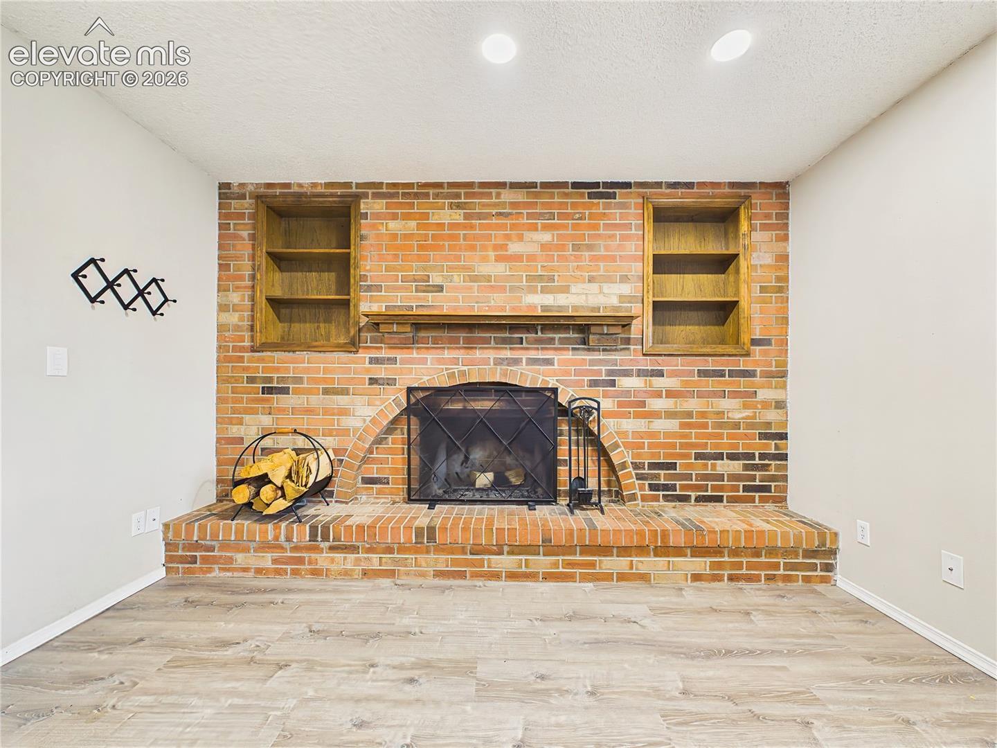 Inviting family room centered around a floor-to-ceiling brick fireplace with built-in shelving and a classic hearth that creates a warm focal point.
