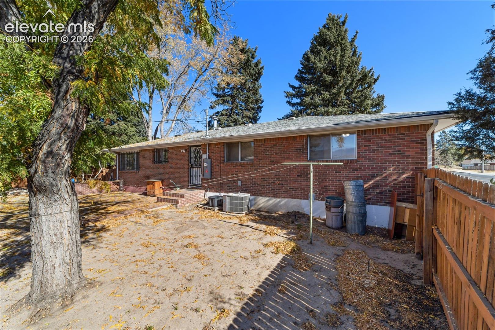 Rear brick exterior featuring multiple windows and a private fenced yard