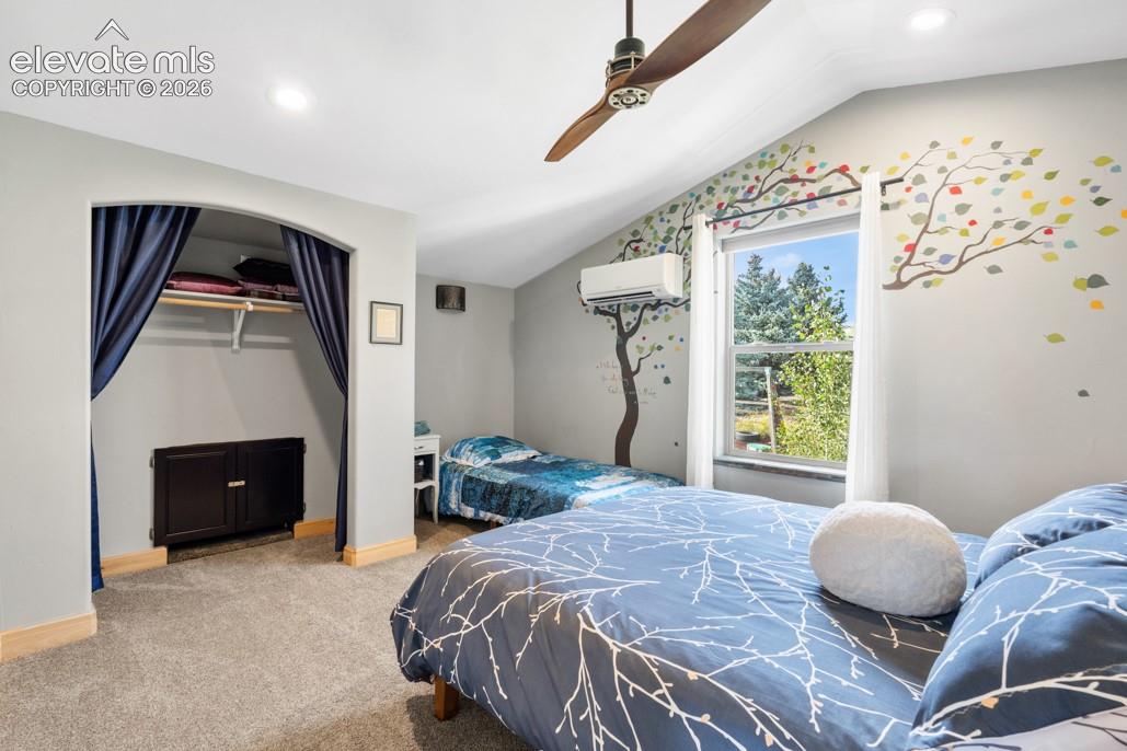 Vaulted ceiling with an integrated ceiling fan, recessed lighting, carpet flooring, a window offering natural light, and a built-in closet with shelving