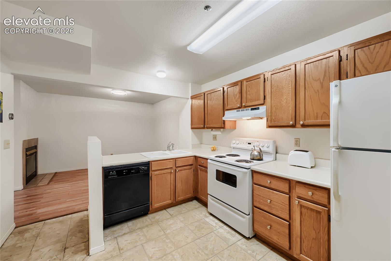 Kitchen featuring wood cabinetry, white countertops, a white electric range, and a white refrigerator