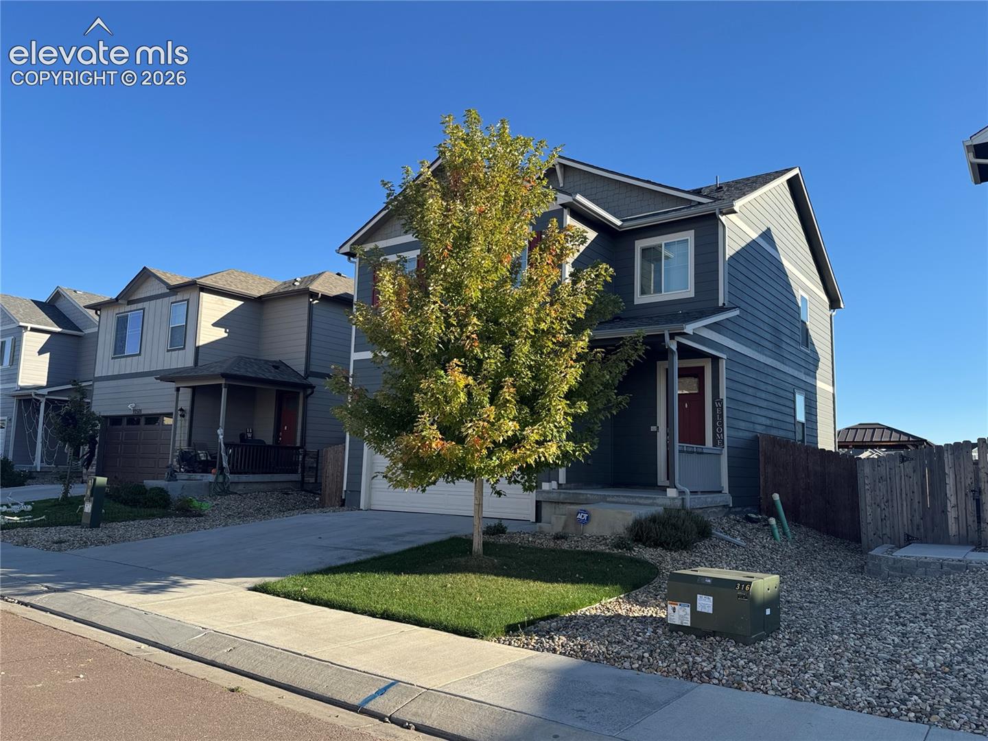 Two-story residence featuring blue horizontal siding, white trim, gabled roofline, front-facing garage, and covered entryway
