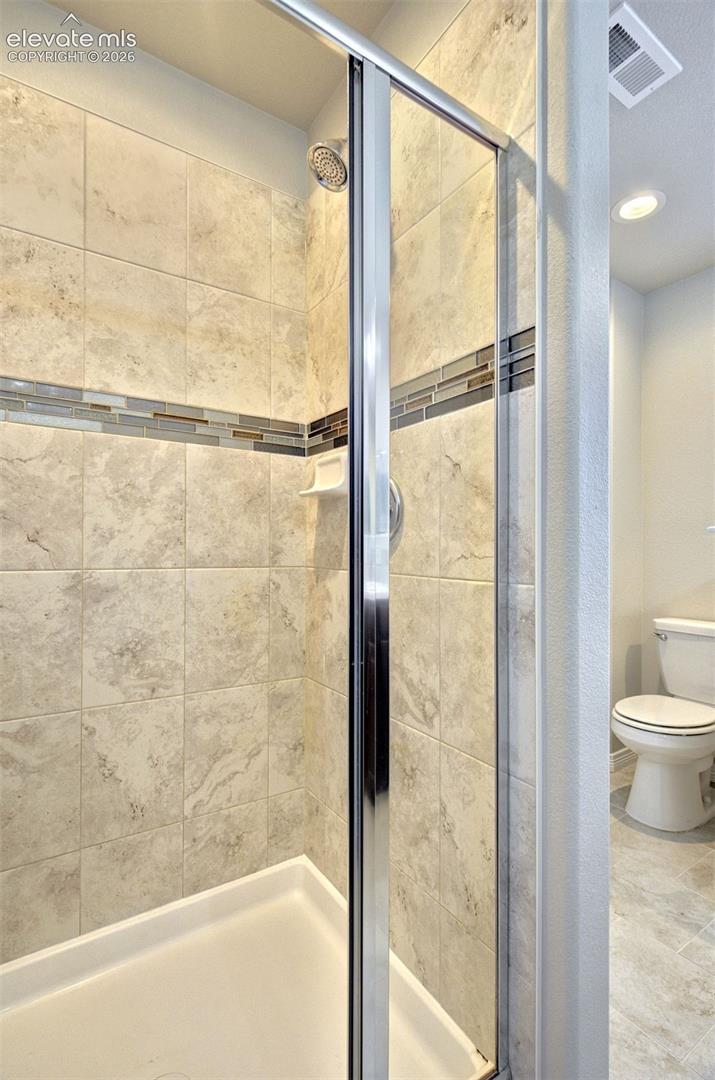 Shower featuring full-height stone-finish wall tile
