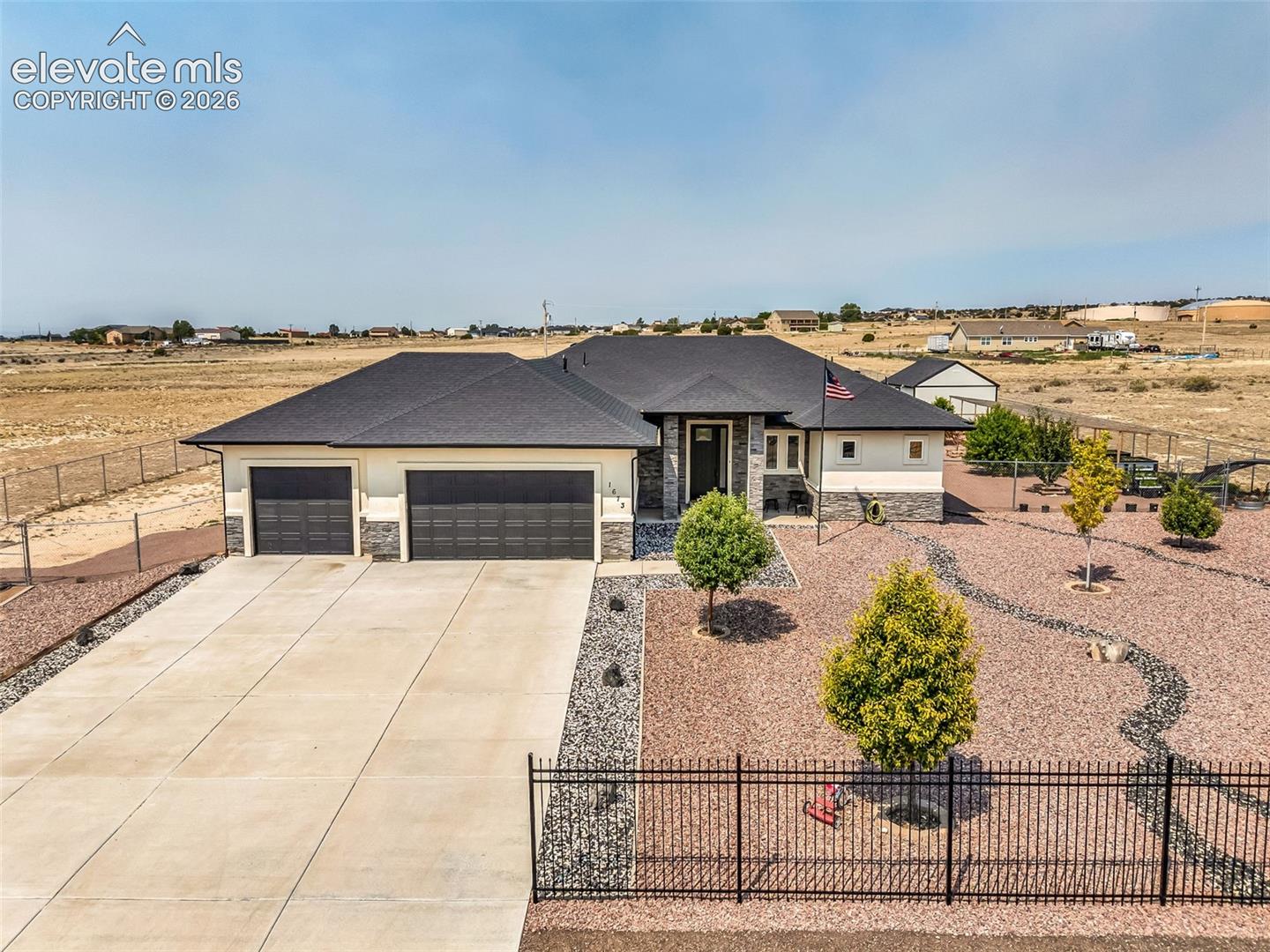Contemporary residence featuring a dark shingle roof and a light-toned exterior with stone accents