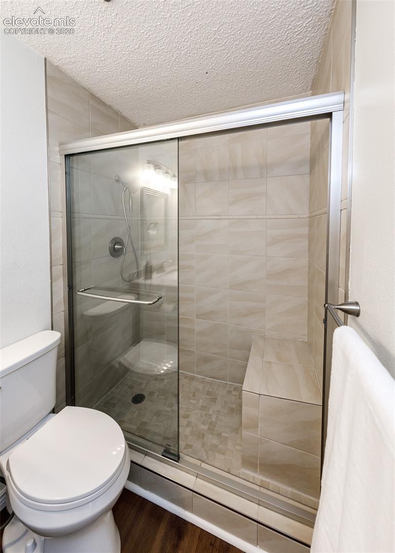 Shower enclosure featuring a built-in tiled bench, glass sliding door, metal hardware, and full-height wall tiling