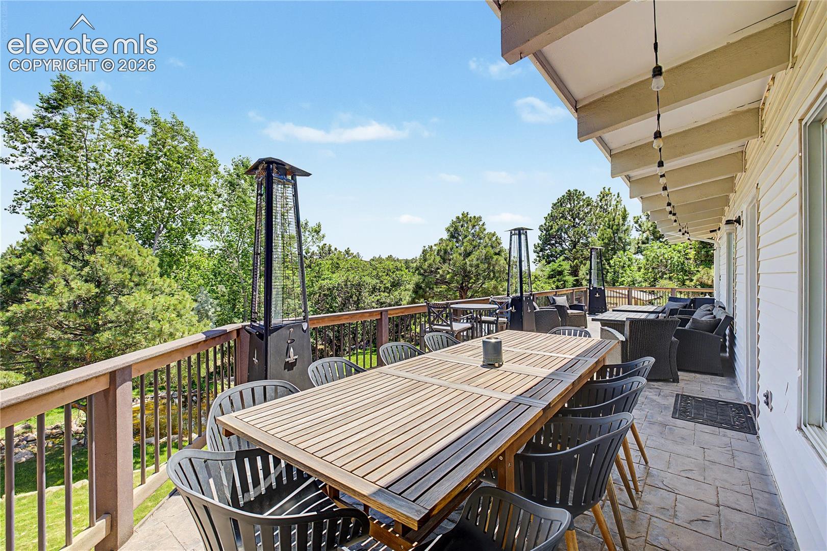 From the far end of the deck, the view opens up over the pond and backyard below, with patio heaters lining the rail for cool Colorado evenings.