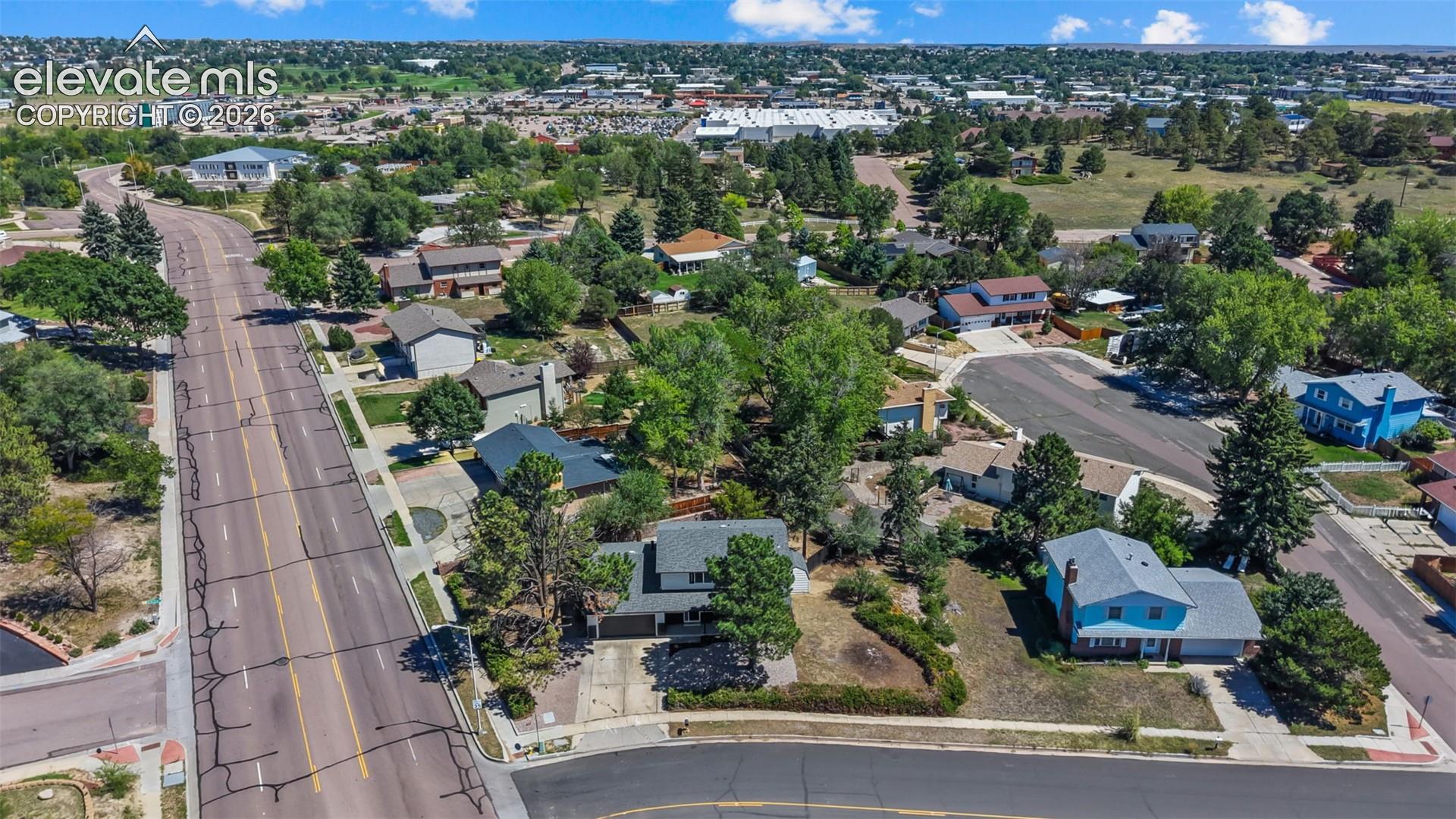 Residential neighborhood with mature trees, visible homes, and paved roads