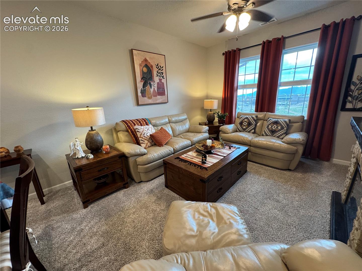 Neutral carpeting, double-pane windows, ceiling fan with integrated lighting, and stone-surround fireplace