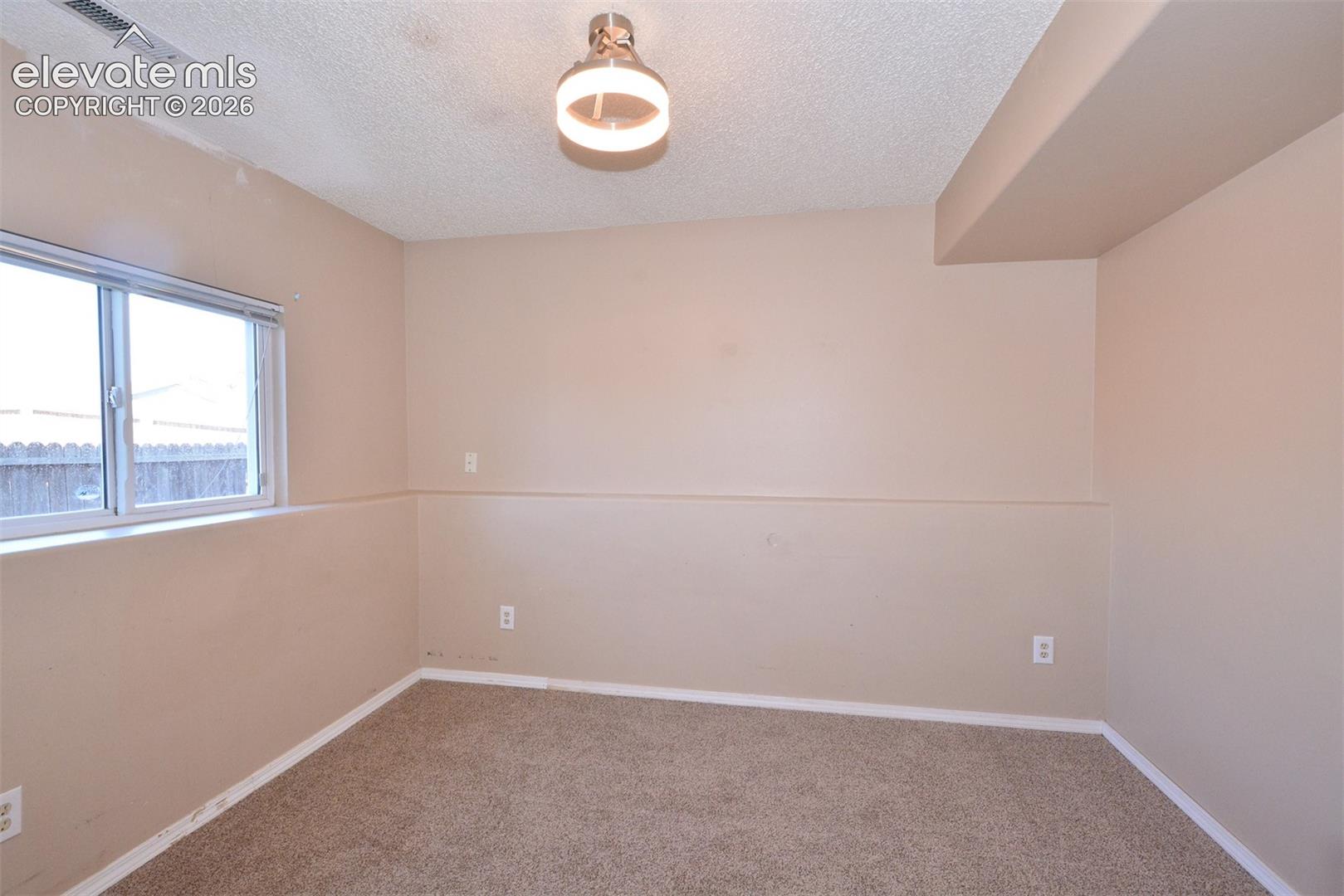 Carpeted room with a single window and recessed ceiling light