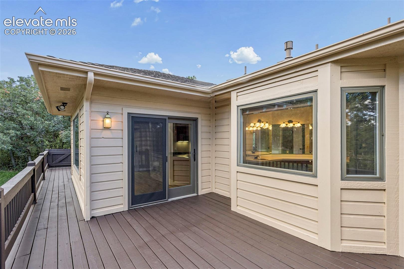 Expansive outdoor deck with a sliding glass door, fixed windows, and exterior lighting