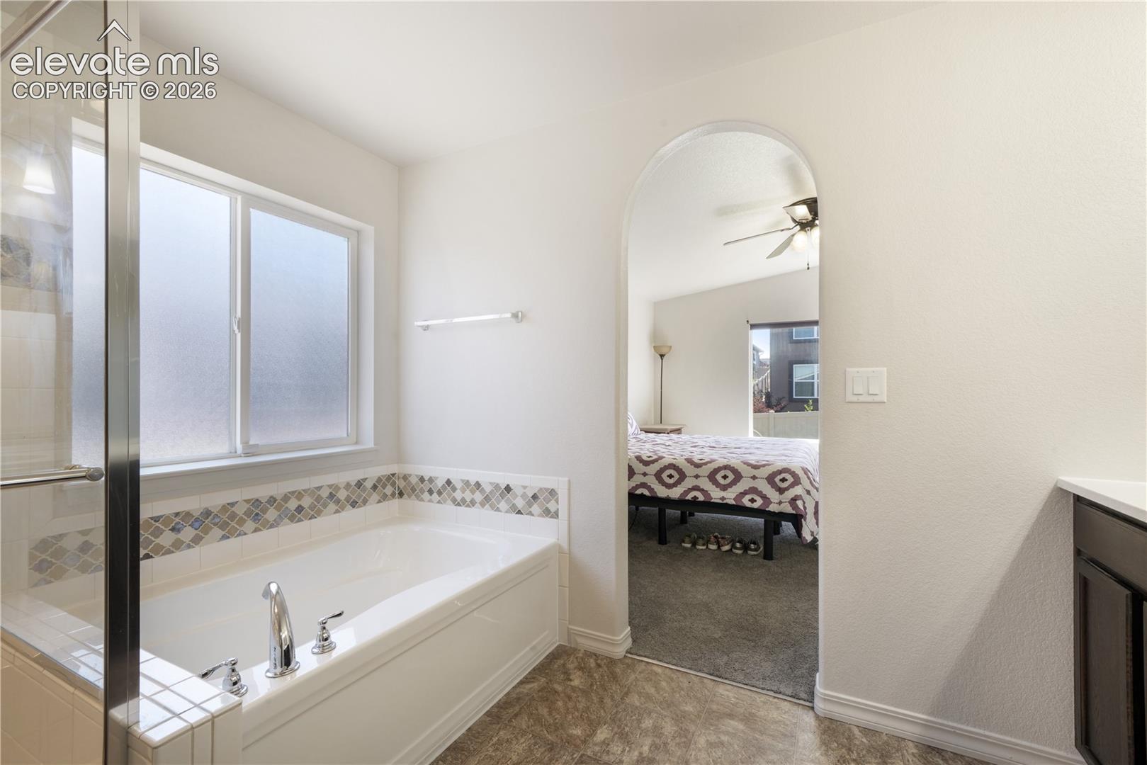Main level primary 5 piece bathroom with dual sinks, granite counters, free standing shower, large bathtub, large walk in closet