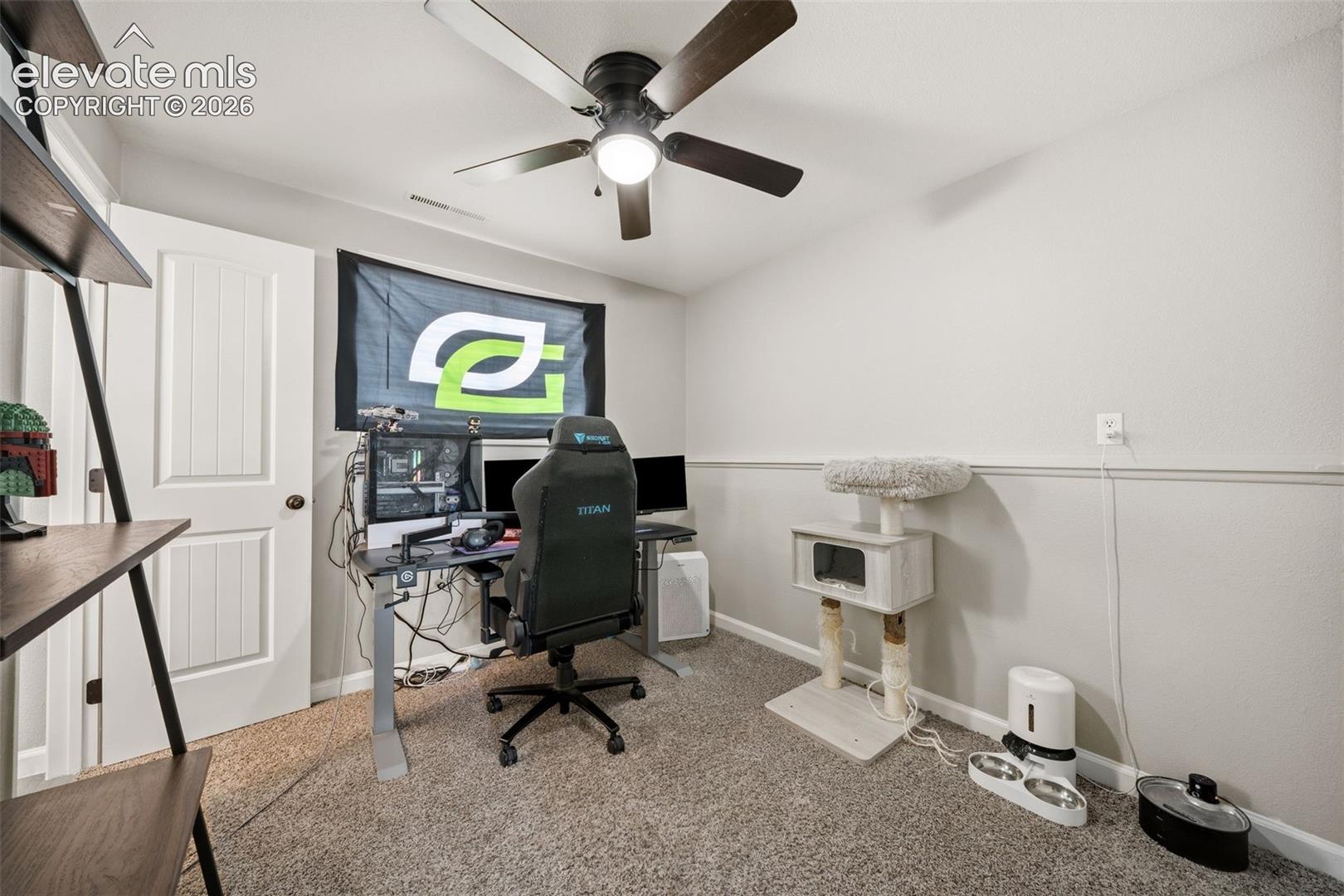 Carpeted room with a ceiling fan, white paneled door, and two-tone wall treatment