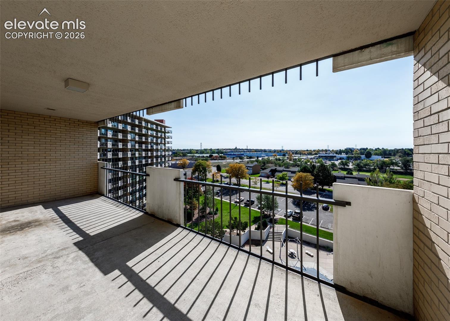 Private balcony featuring concrete flooring, brick wall construction, and vertical metal railing