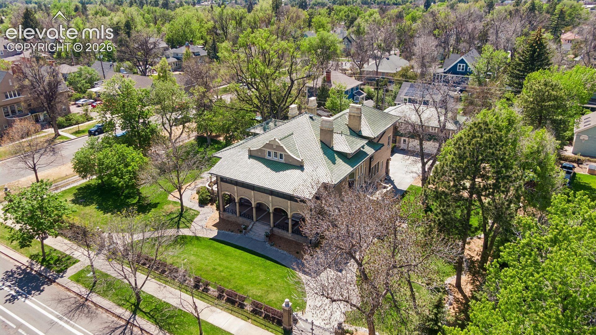 The estate is enclosed by a tall wrought iron fence anchored by stout brick pillars capped with concrete spheres, with electric gate and heated driveway.