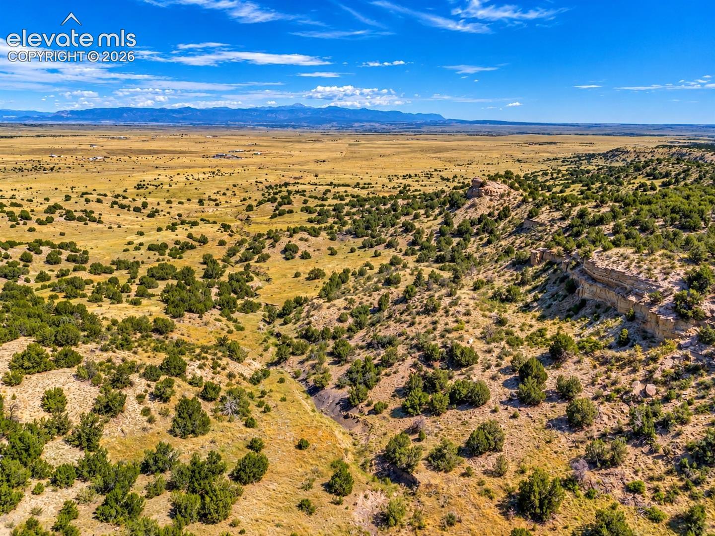Expansive acreage featuring rolling high-desert topography, native juniper vegetation, sandstone rock outcroppings, and prominent mountain backdrops