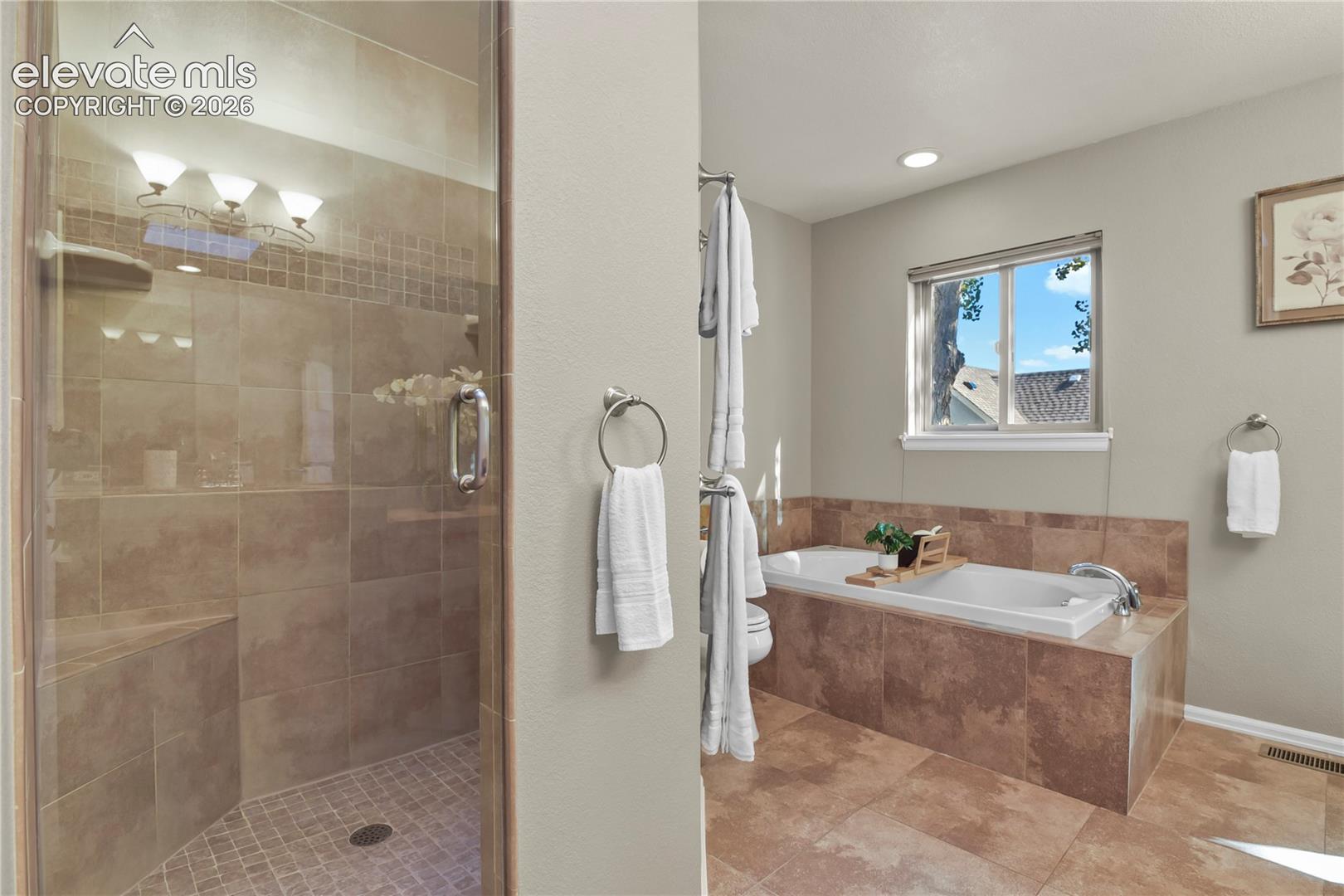 Bathroom featuring a walk-in shower with glass enclosure, built-in tiled bench, soaking tub with tile surround, and tile flooring